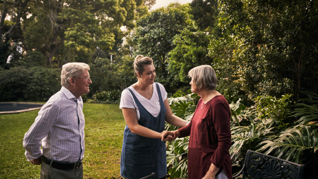 Three people shaking hands in a garden, symbolising trust and connection in conflict resolution and mediation.
