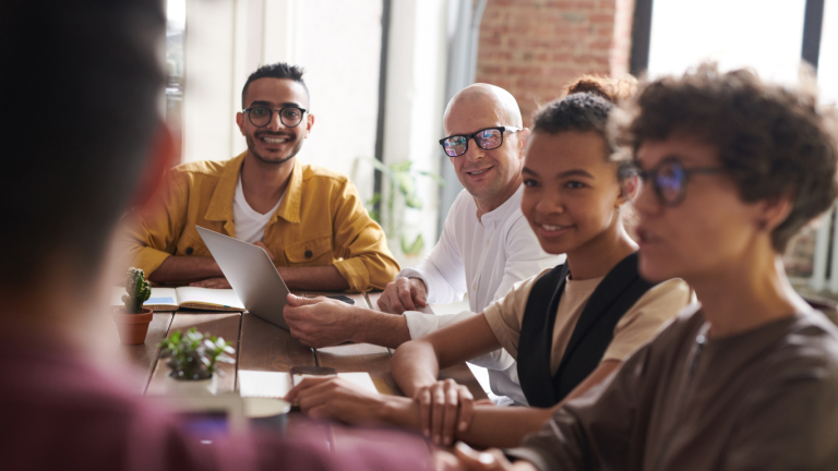 A group of diverse professionals at a table, engaged in a collaborative discussion with a laptop, highlighting a peaceful mediation environment.